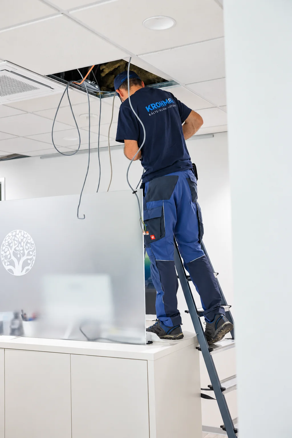 Techniker auf der Leiter bei Arbeiten am Deckengerät